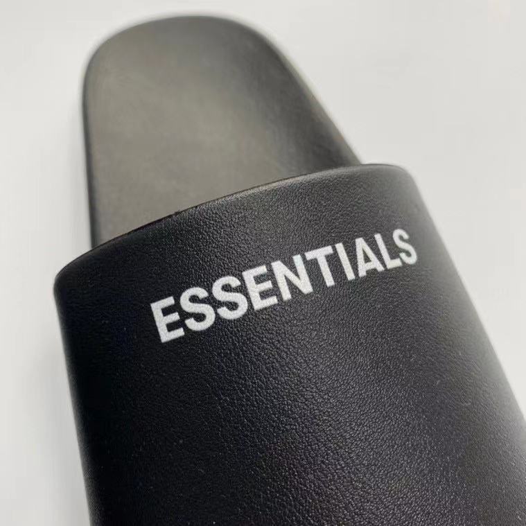 Essentials slide sandal featuring bold black design with "ESSENTIALS" text, perfect for casual K-pop merchandise collection.