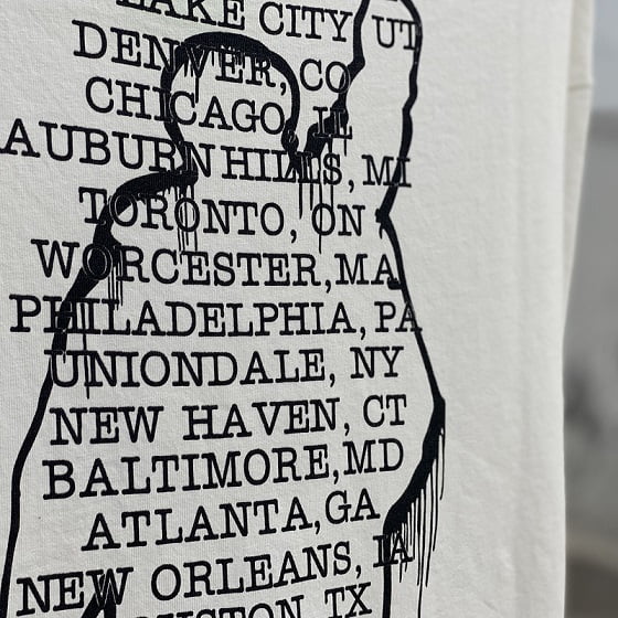 Black-and-white graphic design featuring a silhouette with city names listed inside, representing a popular K-pop band merchandise design.