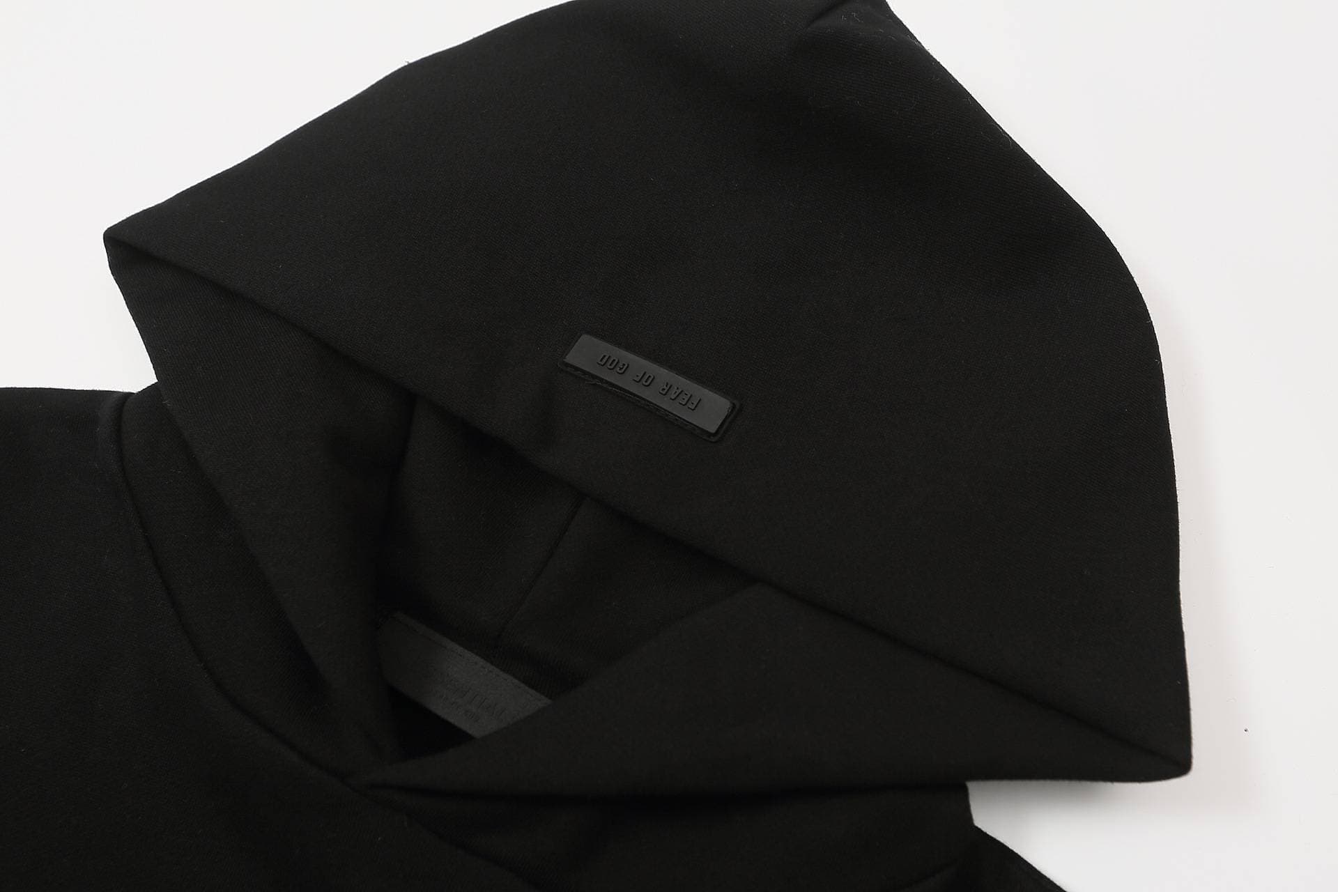 Black hoodie with "FREAK OF GOD" tag, minimalistic streetwear fashion, casual style, black fabric, detailed close-up, versatile daily wear.