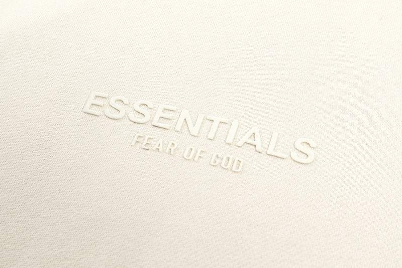 Essentials Fear of God K-pop merch, minimalistic design, white textured background, stylish and trendy, popular among fans, luxury streetwear essentials, upscale clothing brand.